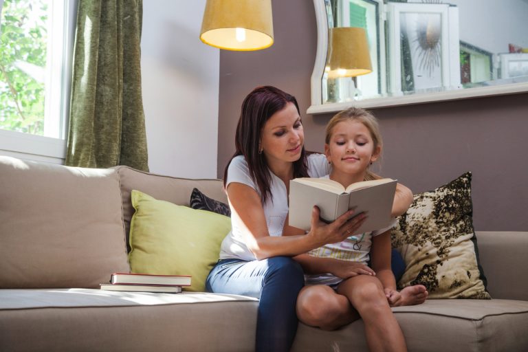 What is Good Parenting: parent and child reading together on a couch with cozy lighting and natural smiles